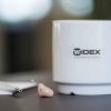 widex-cup-on-table-next-to-a-hearing-aid-1920-1080 (1)